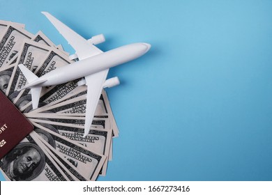 White toy airplane model on a blue background, US dollars and passports, with place for adding text, airfare concept, air freight cost.