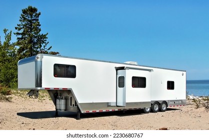 White toy hauler travel trailer camping on the sandy shore of lake Superior  - Shutterstock ID 2230680767