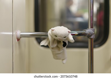 White toy kitten on the handrail in the subway. The child plays everywhere. Somebody lost it. It's suitable for greeting card design, postcard template.