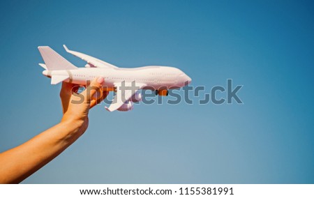 white toy plane in female hand on sunny blue sky background. business traveling and vacation. freedom and inspiration. airmail and postal delivery concept, copy space. travel concept