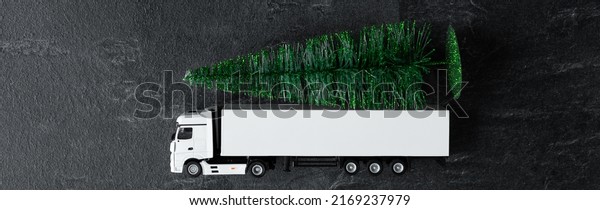 White\
toy truck with christmas tree loaded on the\
back