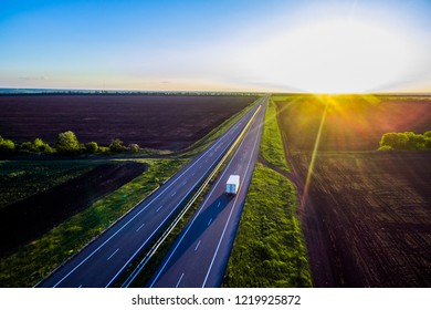 White Trailer Car Driving On Asphalt Road On The Sunset . Road Seen From The Air. Aerial View Landscape. Dron  Photography.