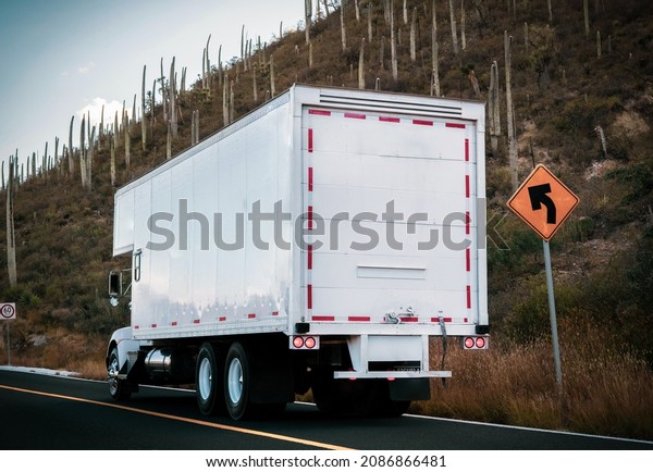 White trailer carrying commercial cargo on the\
highway in Mexico.