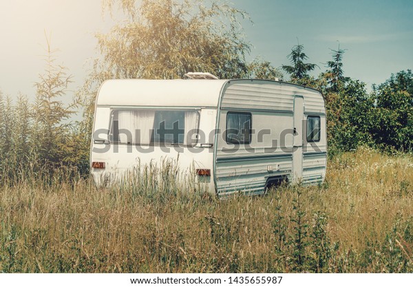 White trailer trailer house on wheels in the\
grass. Affordable\
Housing.