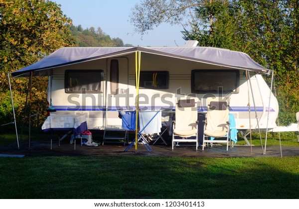 white trailer houses\
are on the campsite with chairs for rest, the theme of outdoor\
recreation and travel\
