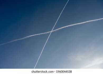 White Trails, From Jet Exhaust, Form A Cross In The Sky. A Blue Sky On The Background