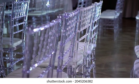 White Transparent Plastic Chiavari Chairs In Rows. Indoor Wedding Ceremony, Event, Seminar Or Party, Stage Blue Light. Concert Hall With No People.