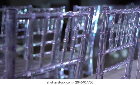 White Transparent Plastic Chiavari Chairs In Rows. Indoor Wedding Ceremony, Event, Seminar Or Party, Stage Blue Light. Concert Hall With No People.