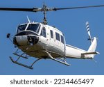 White transport helicopter in flight on a blue sky background