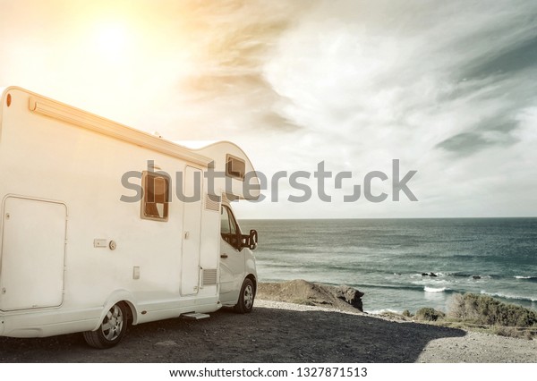 White travel caravan car stay on the\
beautifull ocean coastline with natural view in sunny day. Freedom,\
Family, Travell, Journej, Travelers\
concept.