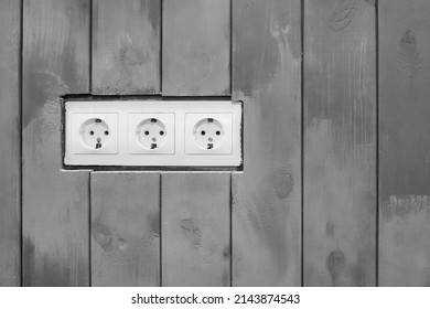 White Triple Power Socket Electric Outlet Plug Voltage On Wooden Painted Gray Color Boards Modern Interior.