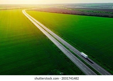 white truck driving on asphalt road along the green fields at sunset. seen from the air. Aerial view landscape. drone photography. cargo delivery - Shutterstock ID 2031741482