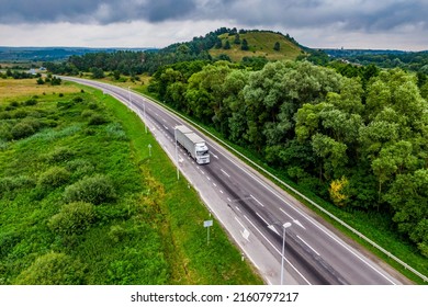 White Truck Driving On Asphalt Road On The Highway. Seen From The Air. Aerial View Landscape. Drone Photography. Cargo Delivery