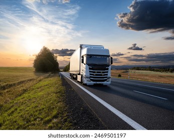 White truck driving on the asphalt road in rural landscape at sunset