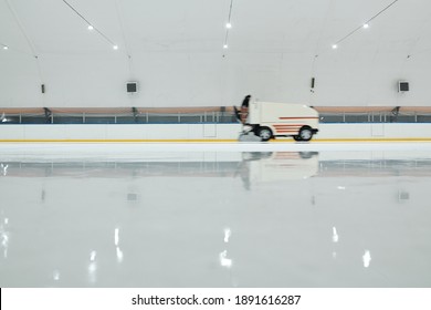 White Truck Or Ice Flattening Machine Moving Along Ice-rink While Preparing It For Playing Hockey Or Skating Inside Large Sports Center