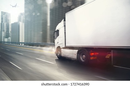 White Truck Moving Fast On The Highway With A Modern City In The Background