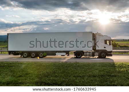 White truck is on highway - business, commercial, cargo transportation concept, beautiful sunset sky, clear and blank space - side view