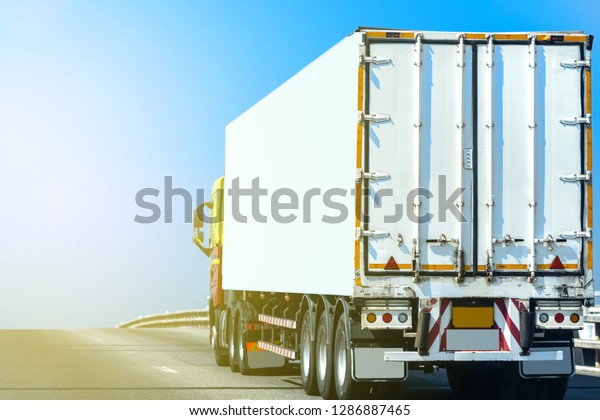 White Truck on highway road with  container,\
transportation concept.,import,export logistic industrial\
Transporting Land transport on the asphalt expressway With the blue\
sky