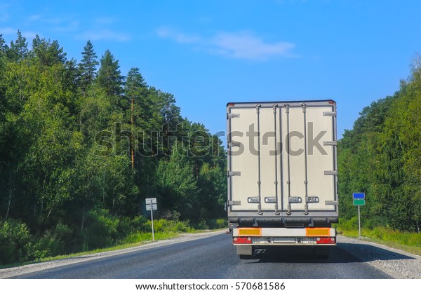 white truck\
transports freight on  country\
highway