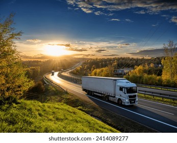 White trucks driving on the highway winding through forested landscape in autumn colors at sunset - Powered by Shutterstock