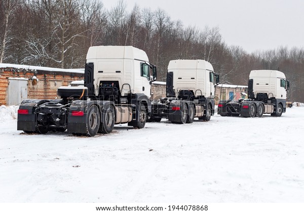 white trucks in\
winter parked on the side of the road. the truck is covered with\
snow. a pack of trucks