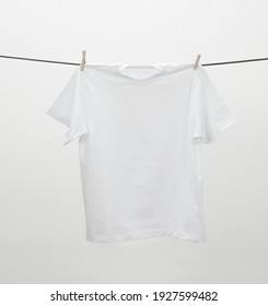 A white T-shirt hanging on a rope to dry on a white background