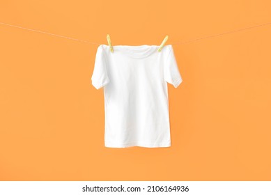 White t-shirt hanging on rope against color background - Shutterstock ID 2106164936