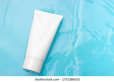 White tube with cream against the background of blue water, copy space