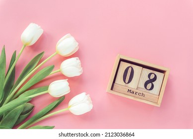 White tulips and wooden block calendar with 8 march date on pink background. Womens day concept. Top view, flat lay