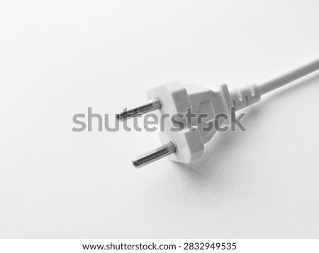 White two prong electrical plug lying on white surface.