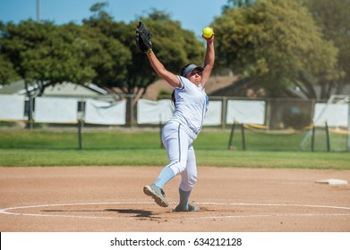 White Uniform Fast Pitch Softball Pitcher Winding Up To Throw In Front View. 