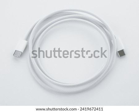 A white USB type C charger cable, compatible for many devices, wrapped in a spiral shape, isolated on white background. White simple USB lightning cable, rolled up