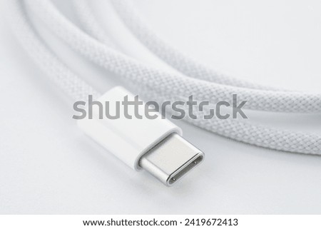A white USB type C charger cable, compatible for many devices, wrapped in a spiral shape, isolated on white background. White simple USB lightning cable, rolled up