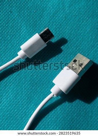 White USB Type-A to USB Type-C charging cable lying on a cyan blue textured background, close-up top view.
