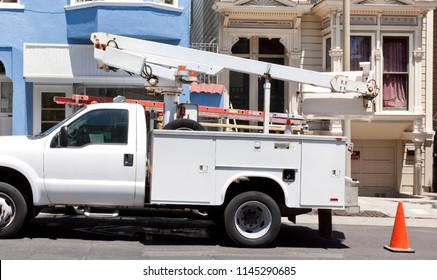 White Utility Truck On Urban Street With Cherry Picker.