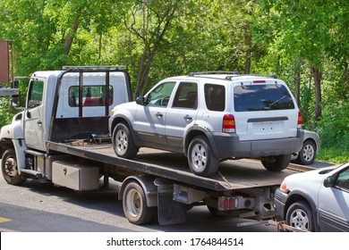 A white van chained to a modern flatbed tow truck. There is also a vehicle being towed.  