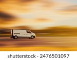 A white van is driving down the street at speed with a blurred background in the color of a yellow sunset. Concept of cargo transportation, goods delivery.