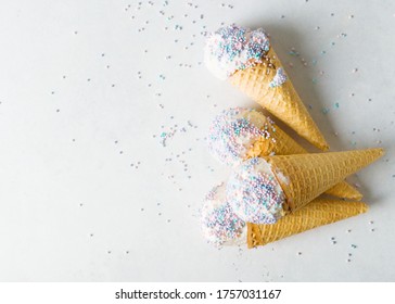 White Vanilla Ice Cream Scoop In Waffle Cone With Sprinkles On Light Grey Background, Top View, Copy Space