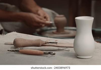 White Vase on Table. Potter's tools. Potter's hands on a Background.