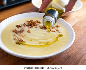 Sopa de crema de verduras blancas servidas con nueces y aceite de oliva en la mesa de madera 