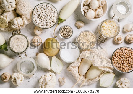 White vegetables and mushrooms, rice, quinoa, legumes, white peppercorns, coconut oil on a white background. Healthy eating and the concept of clean eating. Flat lay, top view, copy space.