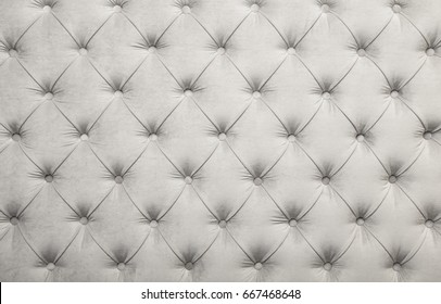 White velvet capitone textile background, retro Chesterfield style checkered soft tufted fabric furniture diamond pattern decoration with buttons, close up