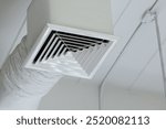 A white vent with a black and white pattern. The vent is in a room with white walls