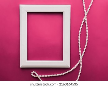 White Vertical Art Frame And Pearl Jewellery On Pink Background As Flatlay Design, Artwork Print Or Photo Album Concept