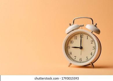 White vintage alarm clock on pastel orange paper background that show time at 9:00 o'clock with copy space. - Shutterstock ID 1793015593