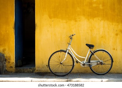 white Vintage bike park near rustic  yellow old wall building. Vietnam city call as yellow city. bicycle vehicles bike easy to traveling in old town spring and summer. Old rusty vintage Retro bicycle 