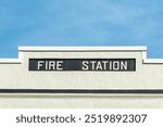 A white vintage concrete building with a black band. The retro fire station