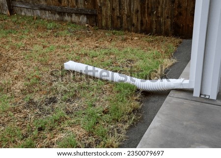A white vinyl downspout extender to divert water away from structures.