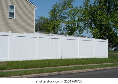 White vinyl fence in a cottage village fencing of private property grass plastic