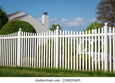 White vinyl fence in a cottage village tall thuja bushes behind the fence fencing of private property grass plastic - Shutterstock ID 2158191693